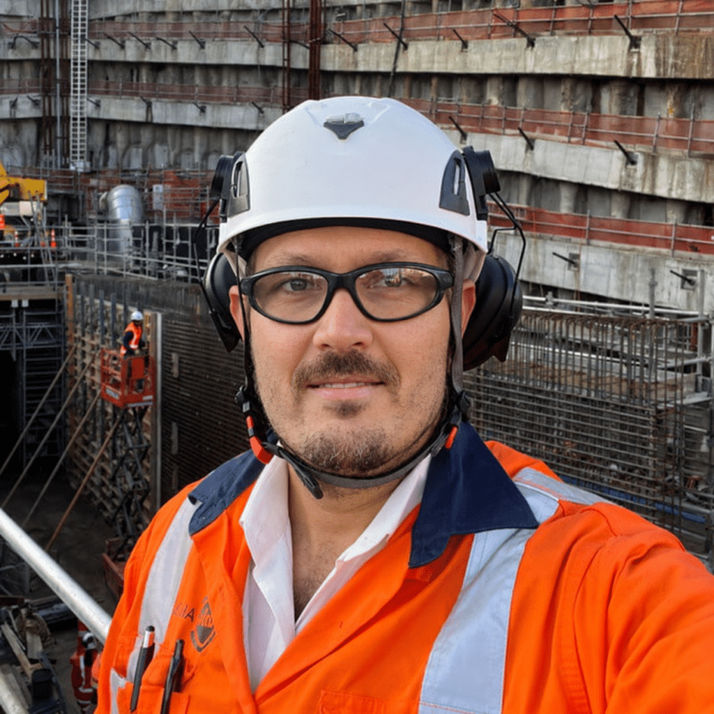 Safety professional wearing a white hard hat and orange high-visibility workwear